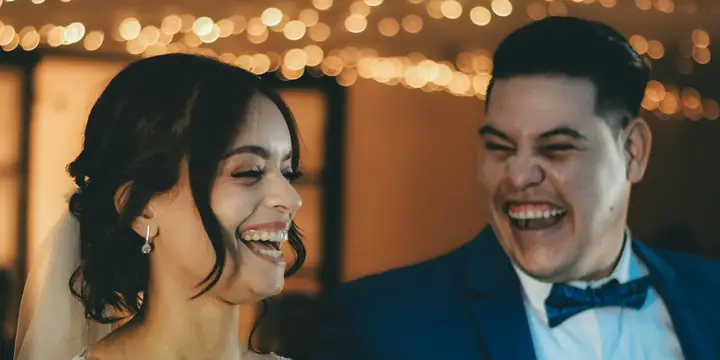 Bride holding a microphone and laughing with the groom at their reception