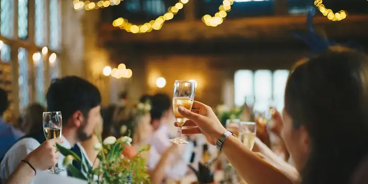 Guests raising champagne glasses at a candlelit wedding dinner
